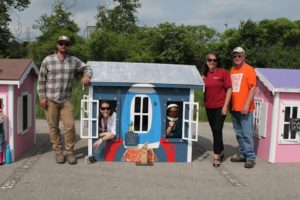 Habitat and CUMIS staff pose with the third-place playhouse, painted blue with a spaceship on the front.