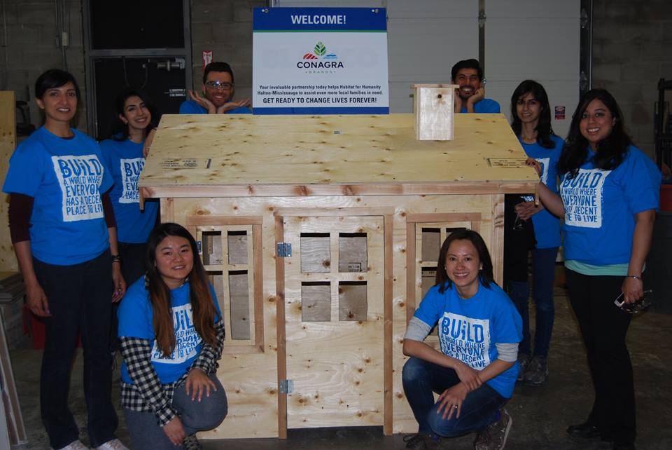 The ConAgra team on the first day of building in ReVive standing around a wooden playhouse.