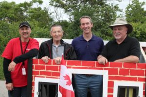 CUMIS employees and Walter Gretzky pose in front of the red-brick Canada playhouse.